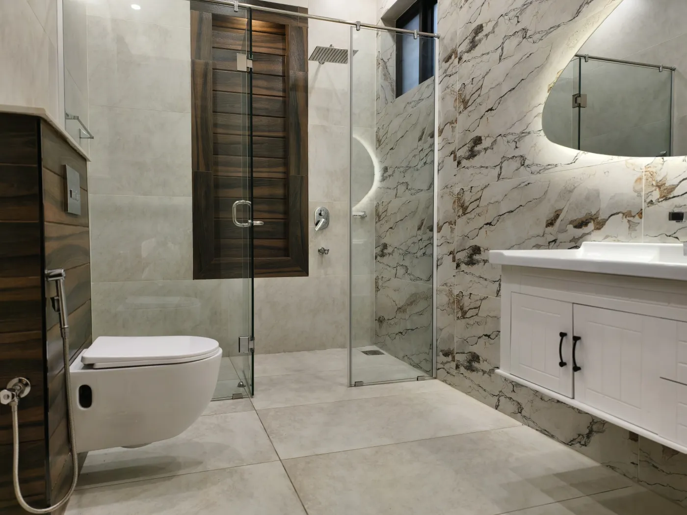 Stone-clad bathroom with backlit mirror and glazed shower